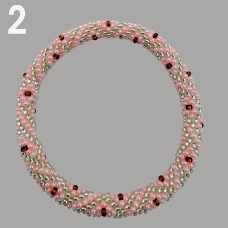 A selection of beaded bracelets in shades of pink, handmade from Nepal.