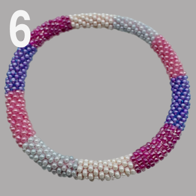 A selection of beaded bracelets in shades of pink, handmade from Nepal.