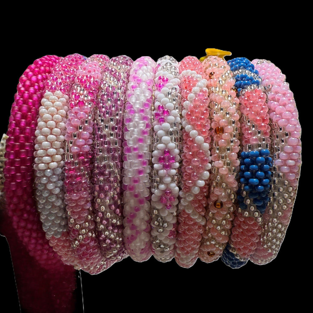 A selection of beaded bracelets in shades of pink, handmade from Nepal.